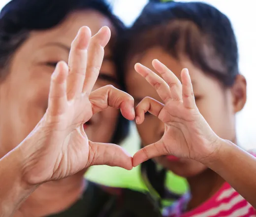 mom and daughter with hands in heart shape